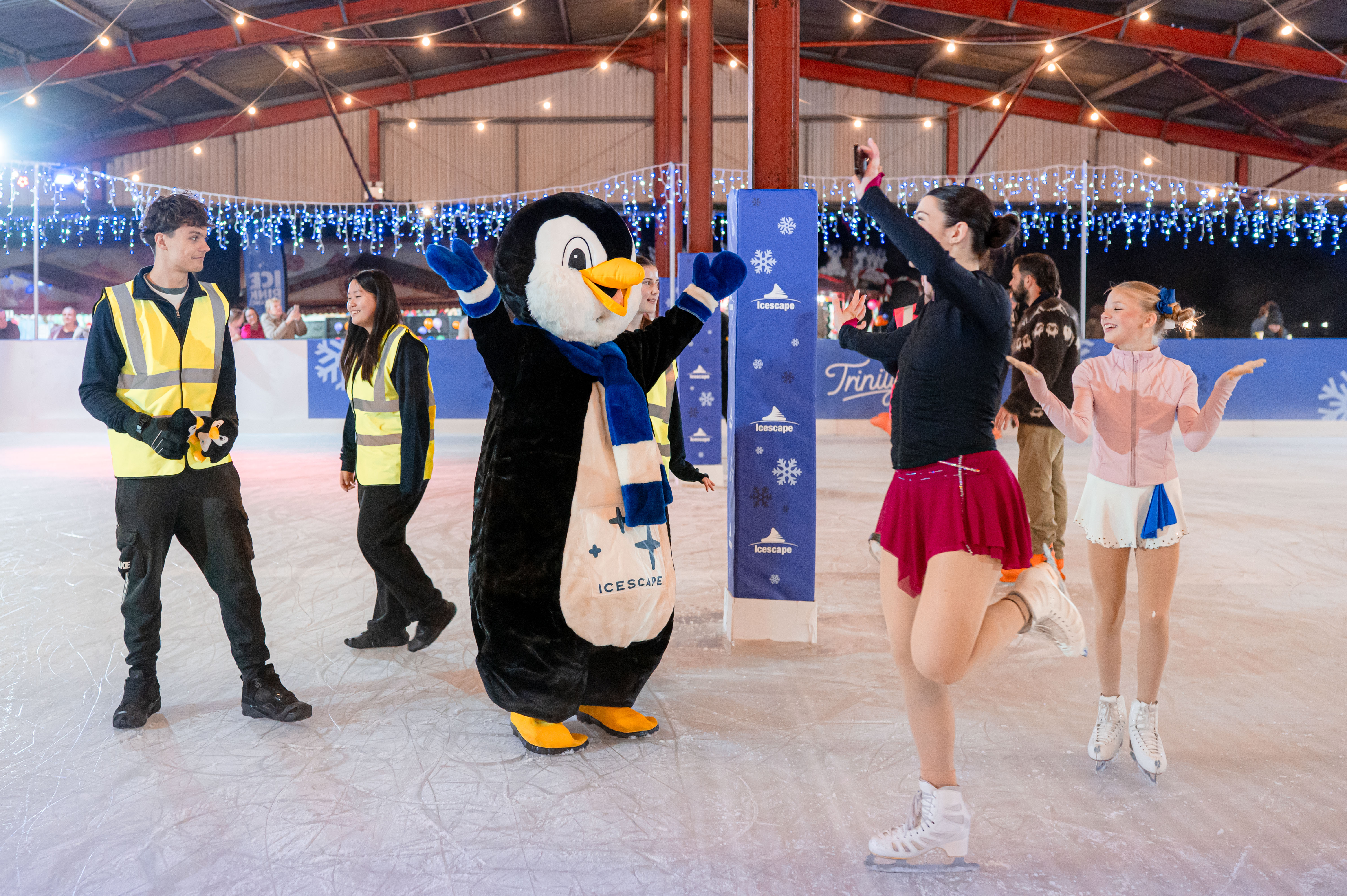 Icescape mascot Pippen the Penguin enjoying time on the ice rink with skaters. 