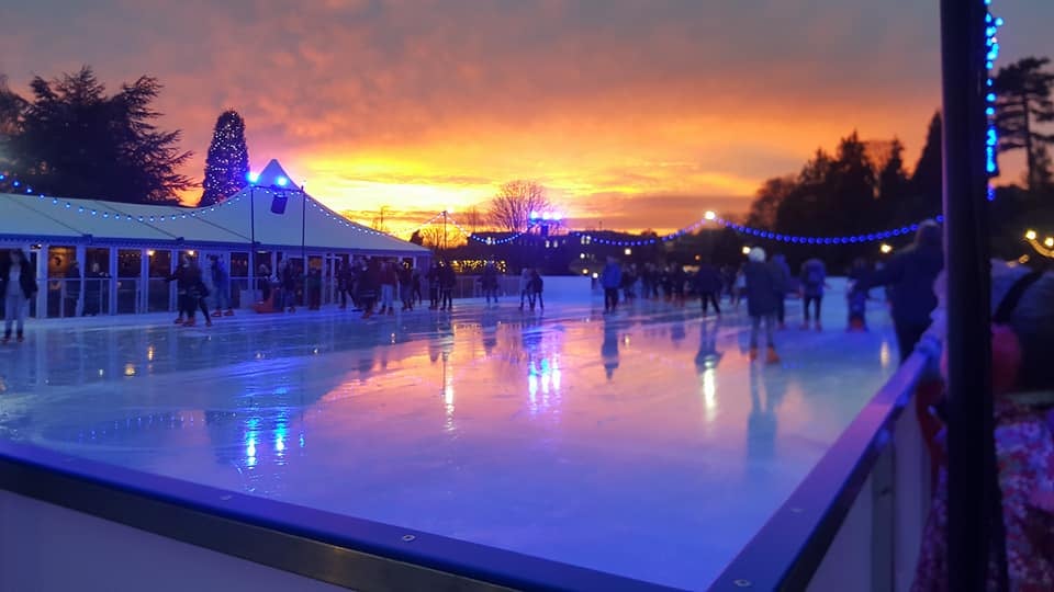 The sun setting in the background whilst skaters are on the ice at Royal Tunbridge Wells winter ice rink. 