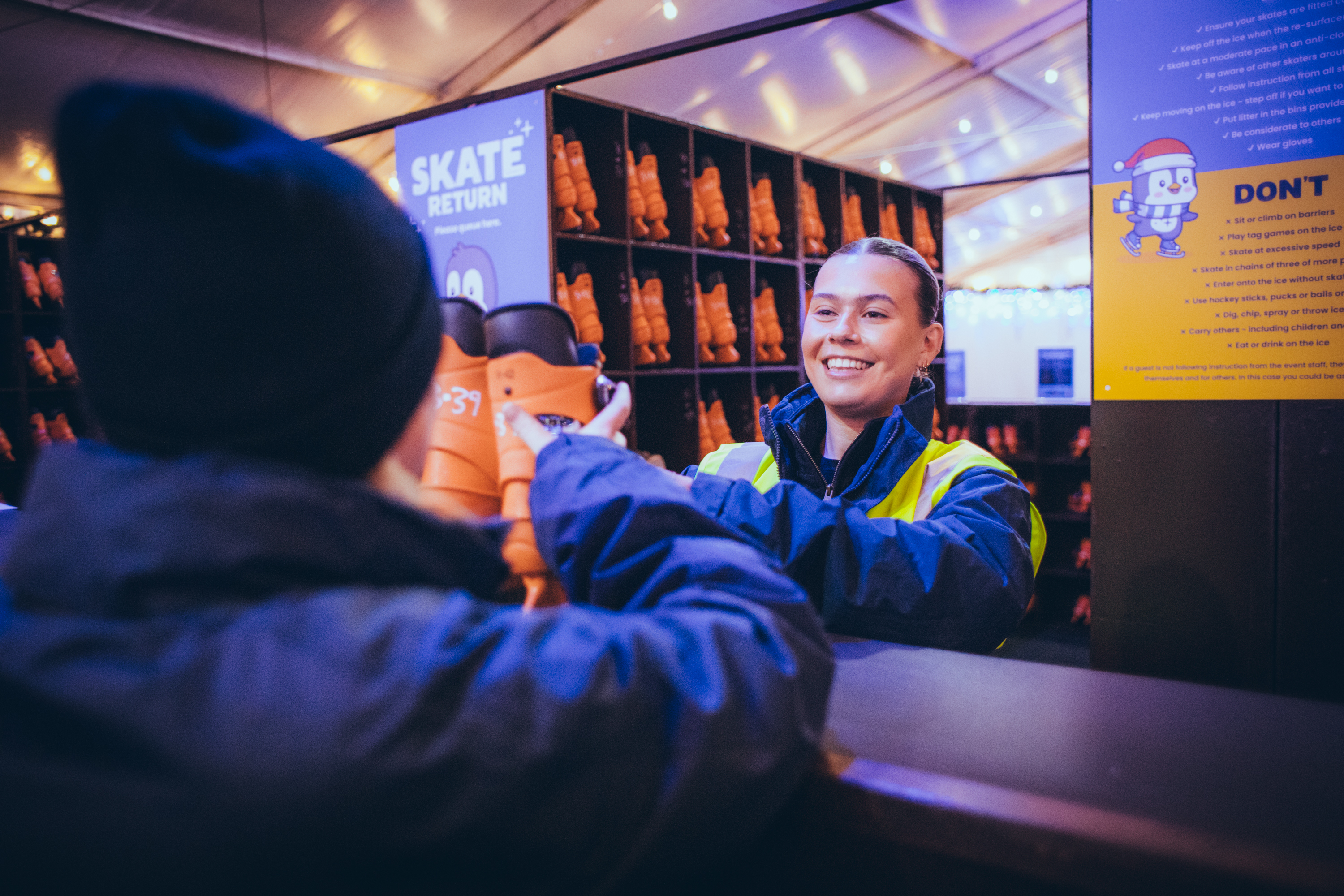A staff member at Icescape Tropicana, handing out ice skates to a customer. 