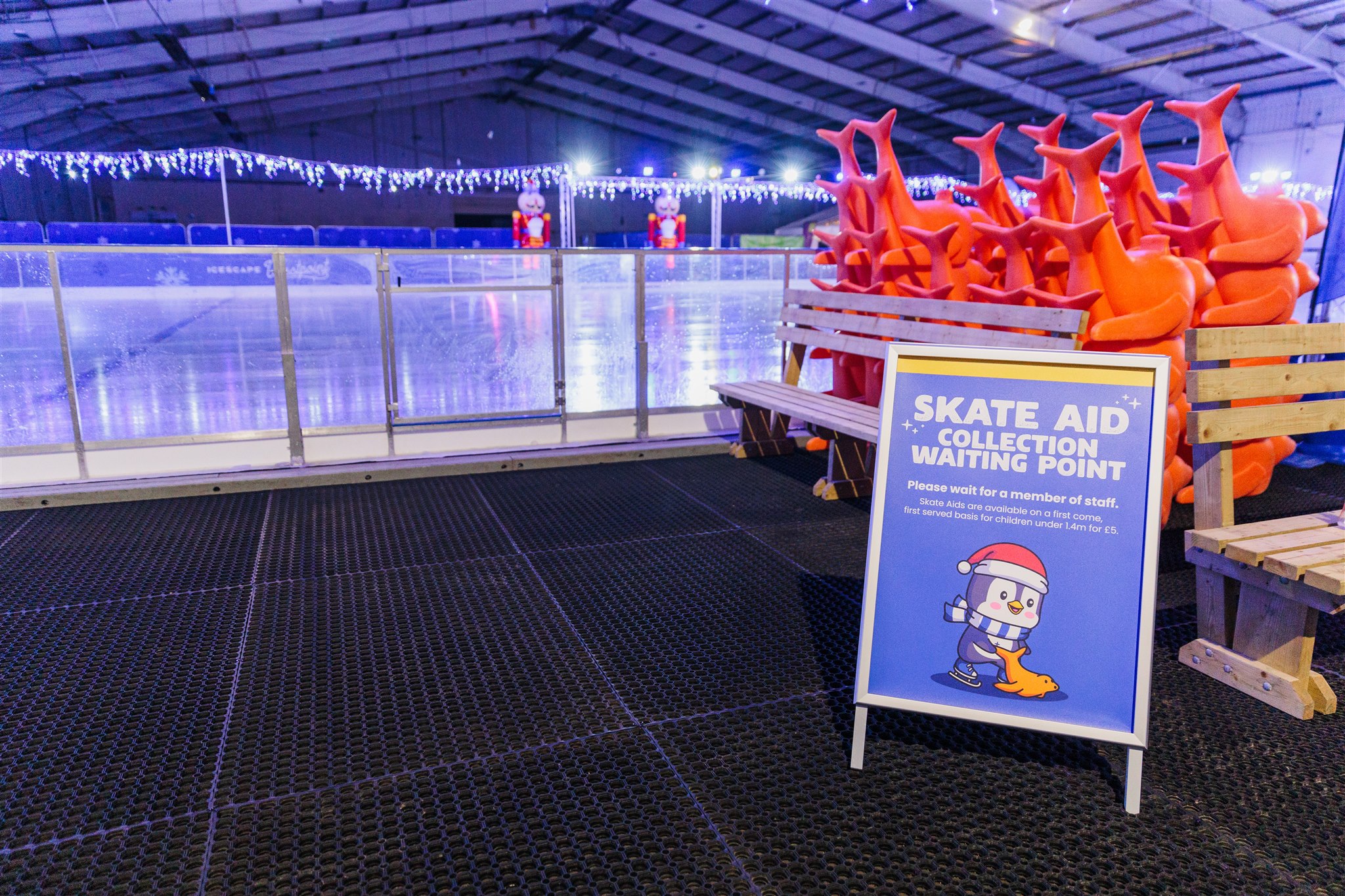 A skate aid collection point sign at Icescape Westpoint. The seal skate aids are stacked behind and the ice can be seen in the background.. 