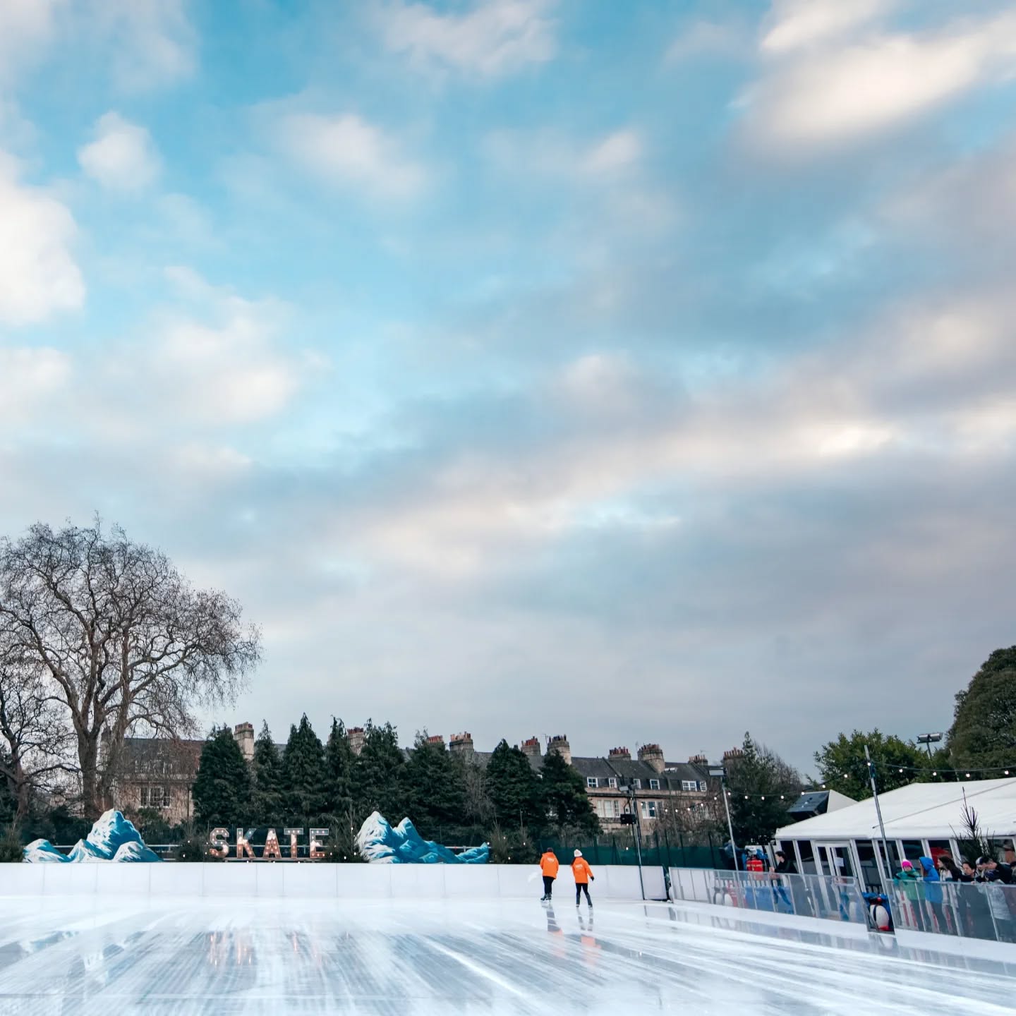 Two Skate Marshalls maintaining an ice rink whilst skaters wait to go on the ice. 