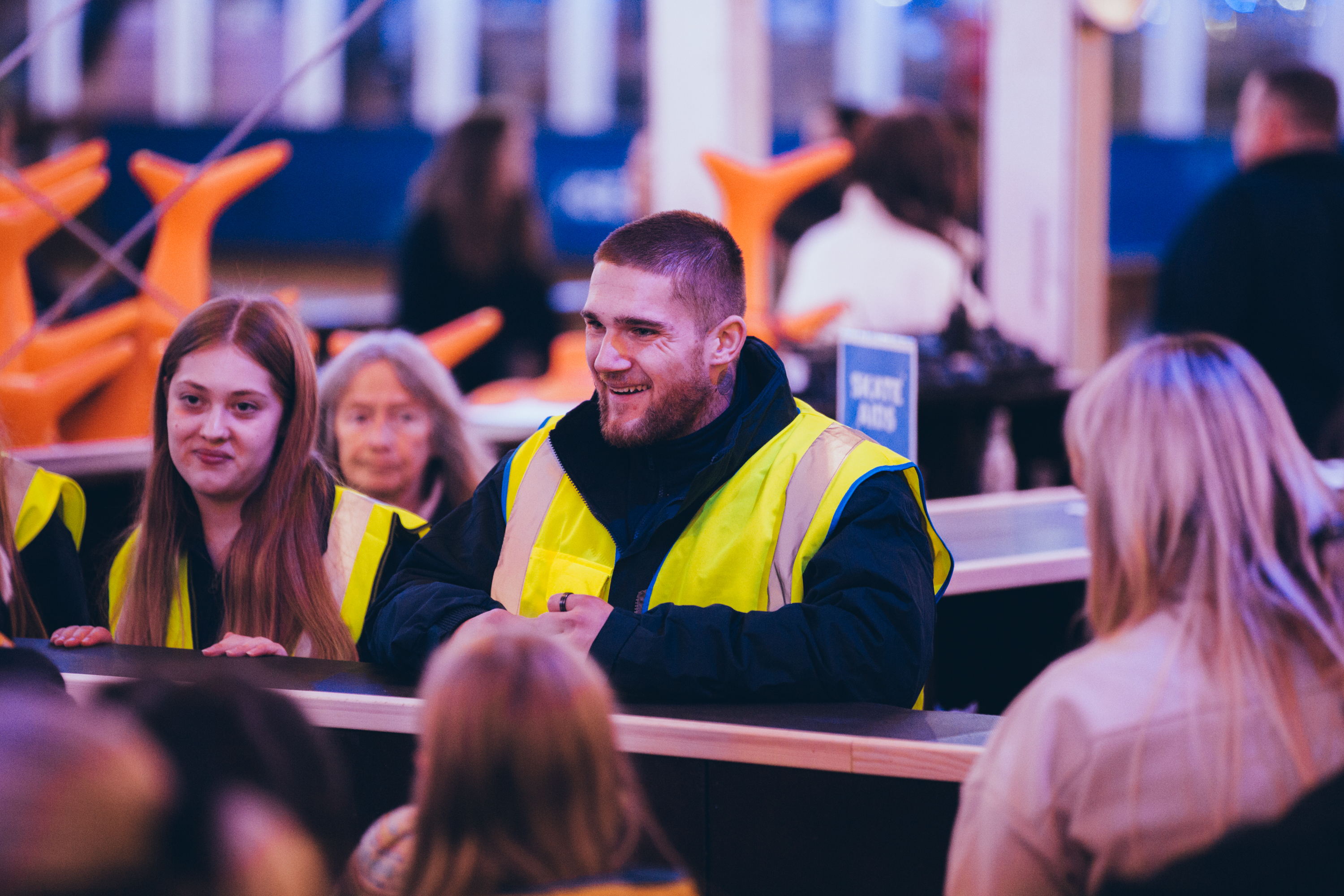 Staff at winter ice rink smiling at guests waiting to receive their ice skates.