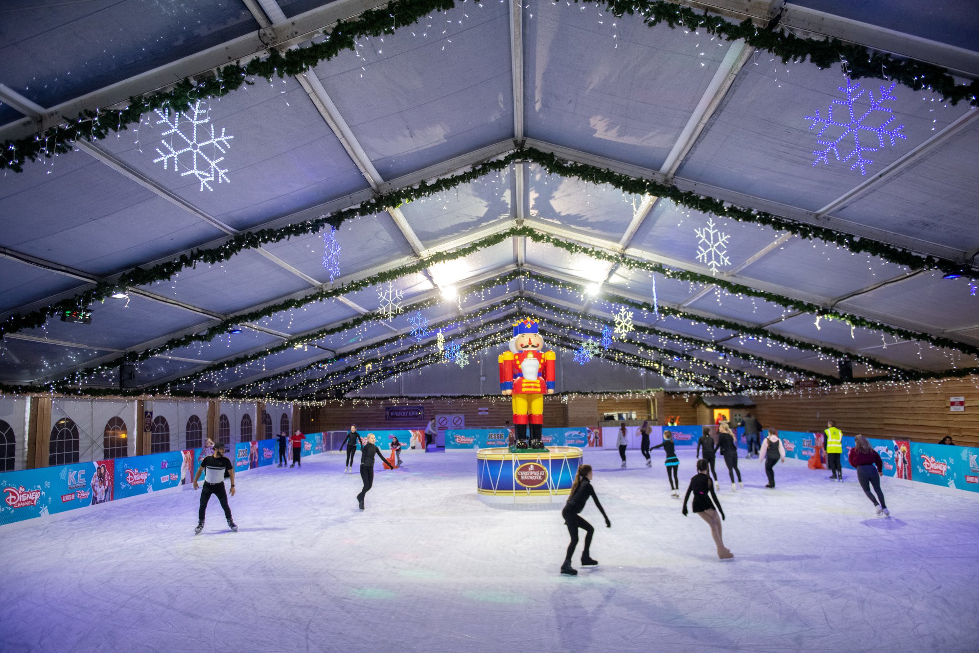 Bluewater winter ice rink. Skaters are skating around two giant nutcrackers in the middle of the ice and the rink branding is Disney. 